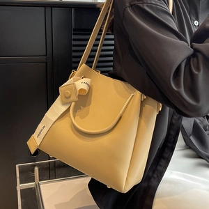Minimalist beige bucket handbag with fashion strap and gold hardware in luxury setting