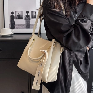 Large cream leather bucket bag for women featuring stylish fashion ribbon and top handle