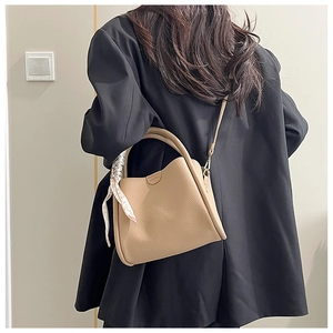 Détail du sac à main en cuir kaki avec texture grainée et poignée décorée d'un foulard