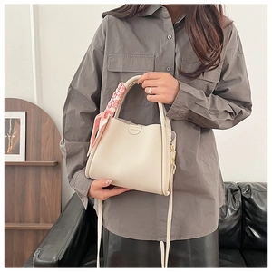 Detail of cream bucket bag with lychee texture, silk scarf handle and HOCONU logo