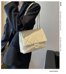 Quilted cream chain bag on a model wearing black suit with minimalist gray background