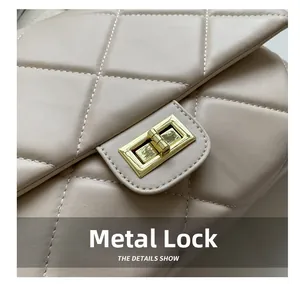 Detailed macro view of the gold rectangular metal lock on a quilted leather handbag