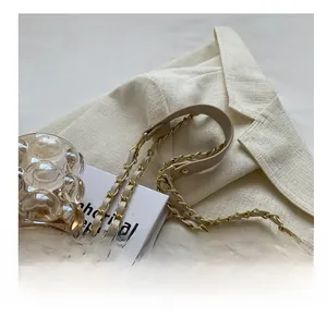Close-up of beige quilted handbag with metal chain strap and leather shoulder pad