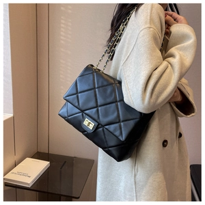 Side view of black quilted crossbody bag with gold chain strap and turn-lock closure