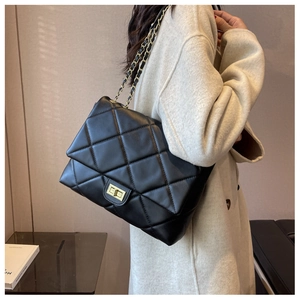 Detailed view of quilted black leather shoulder bag with gold chain and turn-lock