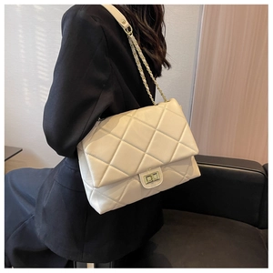 Detail of beige quilted crossbody bag featuring gold twist lock and chain strap on model