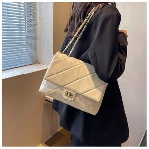 Close-up of beige quilted shoulder bag with gold chain and metal twist lock detail
