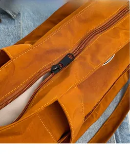 Detailed macro view of the smooth metal zipper and precision stitching on the canvas tote