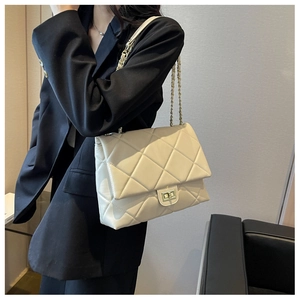 Detail of quilted diamond pattern and gold metal clasp on beige chain shoulder bag