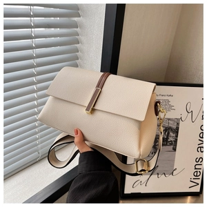 Detail of creamy white pebble leather crossbody bag with wide strap and gold hardware