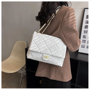 Detailed back view of a white quilted leather shoulder bag with gold chain strap on a model