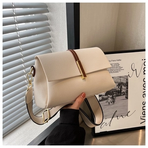 Detail of beige lychee leather crossbody bag featuring wide strap and gold hardware