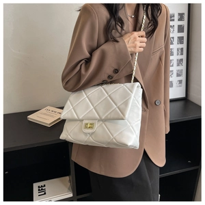 Detail of white quilted leather chain bag with gold twist lock on a shoulder strap