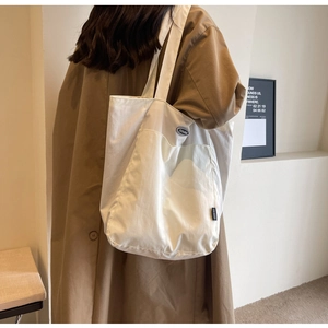 Detailed side view of a large white canvas tote bag with broad shoulder straps on a model