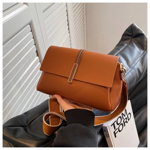 Detailed shot of caramel leather square bag with gold buckle and wide shoulder strap