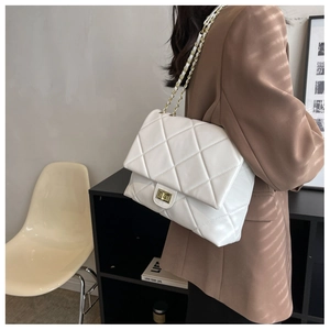 Detailed close-up of white quilted PU leather bag with gold chain strap on a model