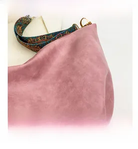 Detail of pink faux suede shoulder bag with retro bohemian embroidered wide strap