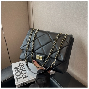 Detailed view of black quilted crossbody bag with gold chain and metal twist lock closure