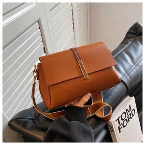 Detailed macro view of the brown litchi pattern leather and gold metal buckle hardware