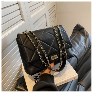 Close-up of black quilted leather shoulder bag featuring gold chain and turn-lock closure