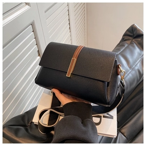 Detail of black lychee grain crossbody bag with striped wide strap and gold hardware