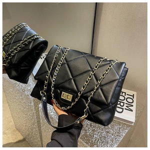 Macro detail of black quilted leather shoulder bag with golden chain and twist lock