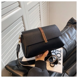 Close-up of black lychee grain leather crossbody bag with wide woven shoulder strap