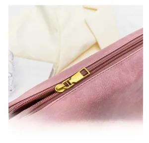 Detailed close-up of smooth gold metal zipper and pink leather material on bucket bag