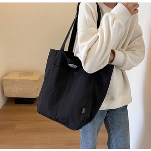 Detail of the high-capacity black canvas tote bag with DOUGU brand logo and woven label