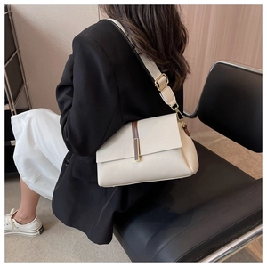 Detail of cream leather shoulder bag with wide strap and brown trim on black blazer