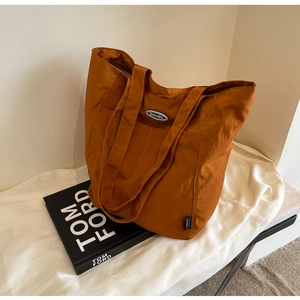 Detailed close-up of a caramel brown large tote bag with brand logo and nylon texture