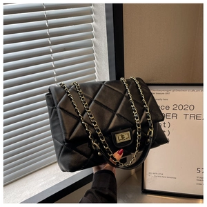 Detail of black quilted leather shoulder bag with gold chain strap and twist lock