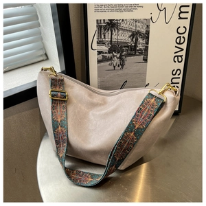 Detail of hobo bag featuring wide ethnic-style strap and golden metallic hardware