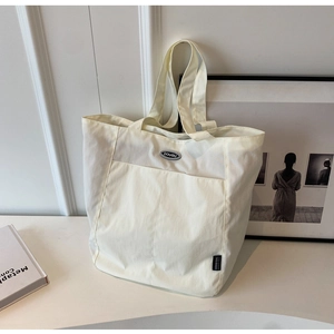 Close-up of minimalist cream white canvas tote bag with front pocket and brand logo