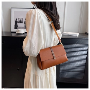 Brown lychee leather shoulder bag with wide strap and gold metal detail on model