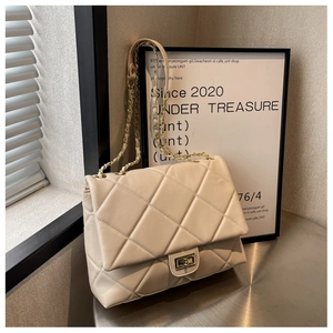 Macro detail of creamy quilted faux leather texture with golden twist lock and metal chain