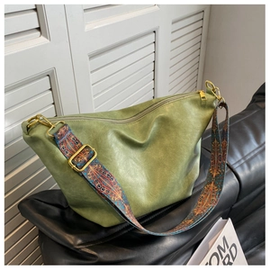 Macro shot of green faux leather bag with bohemian patterned wide shoulder strap