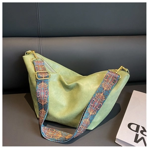 Detail of green hobo bag featuring ethnic style woven strap and gold metal hardware