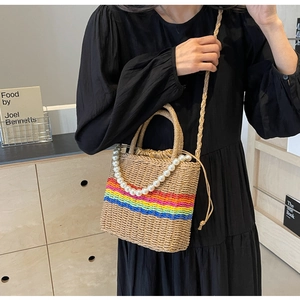 Close-up of rainbow woven straw bucket bag with pearl handle and drawstring closure