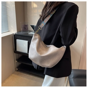 Detail of wide ethnic embroidered strap and glossy grey hobo bag with gold hardware