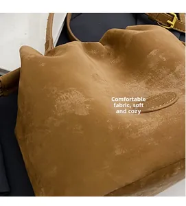 Close-up of the soft matte brown leather texture and delicate stitching on the bucket bag