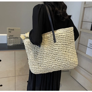 Detail of hand-woven straw tote bag with slim leather straps in a minimalist lifestyle setting