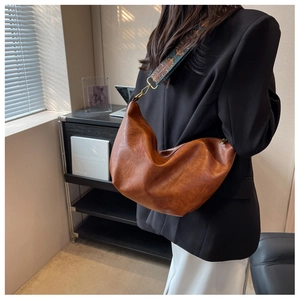 Detail of soft brown leather bag featuring an ethnic jacquard wide shoulder strap