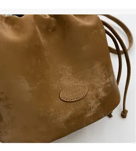 Detail of a brown bucket bag showing retro texture and C&HEKA brand leather patch