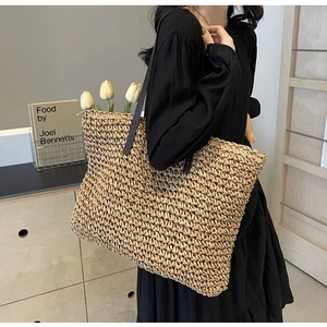 Detail of handwoven straw tote bag featuring sturdy dark brown leather shoulder straps