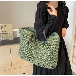 Detail of green straw woven tote bag with dark brown leather straps and large capacity
