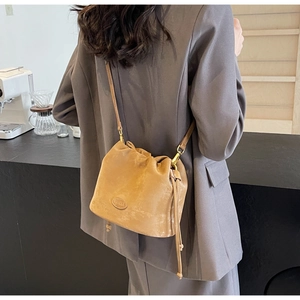 Close-up of matte tan bucket bag with drawstring closure and vintage leather logo detail