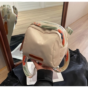 Detail of cream canvas crossbody bag with decorative floral pattern wide shoulder strap