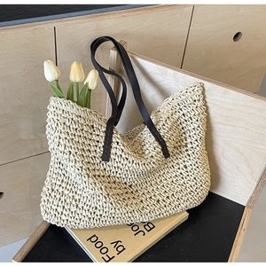 Detail of hand-woven beige straw tote bag with premium brown leather handles and tulips