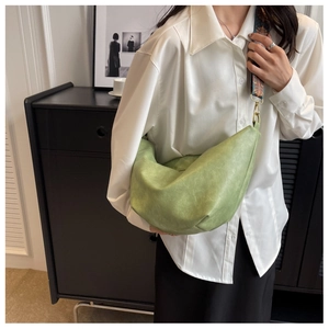 Detail view of a light green crescent bag featuring a vintage embroidered wide strap